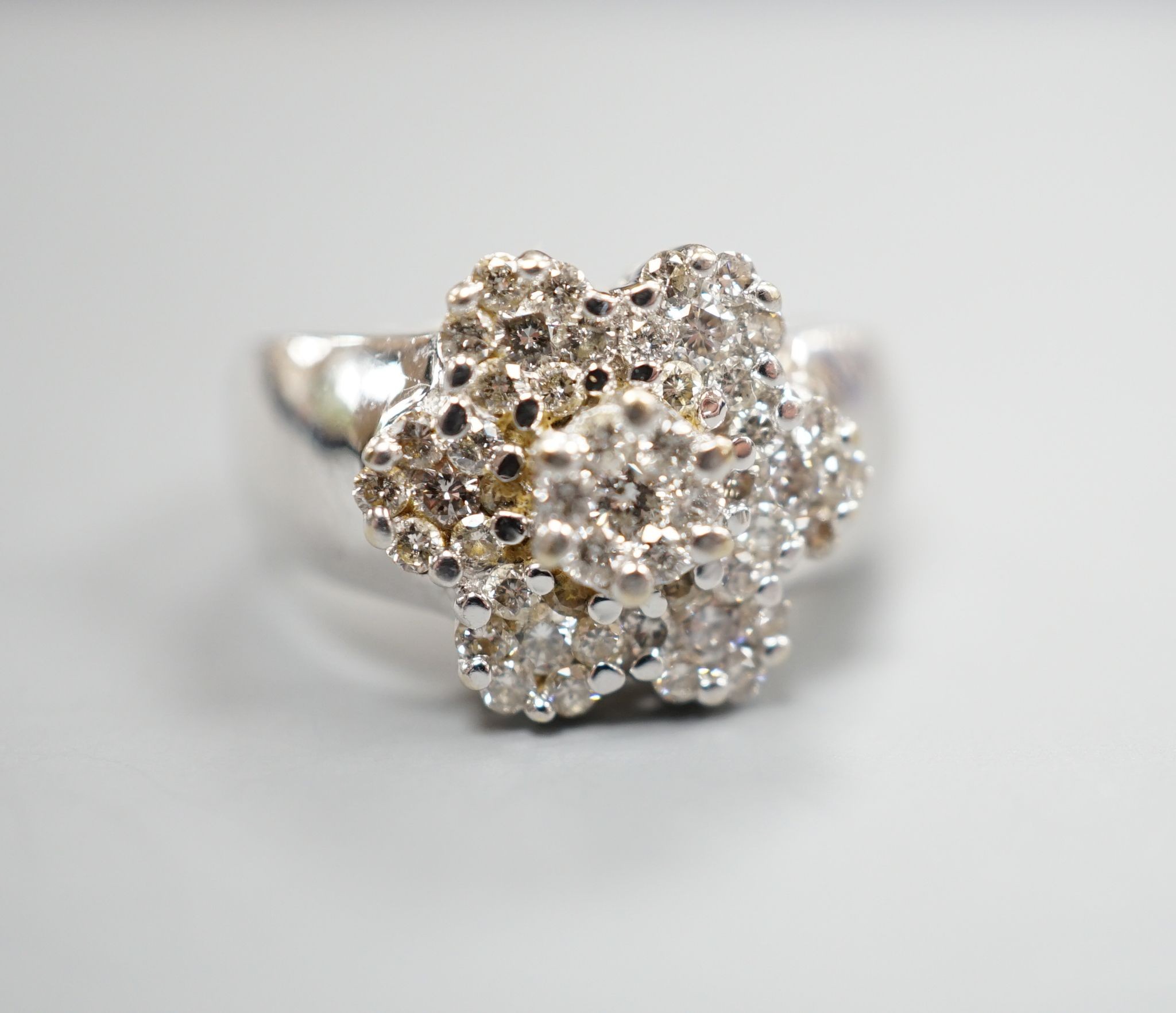 A modern 14k white metal and seven stone diamond set multi-cluster flower head dress ring, size M/N, gross weight 8.4 grams.